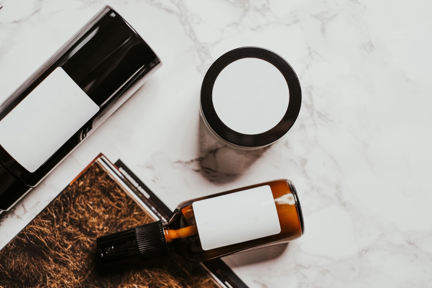 Sticluțe cosmetice și o sticlă deschisă cu formulă pe bază de etanol pe o suprafață de marmură