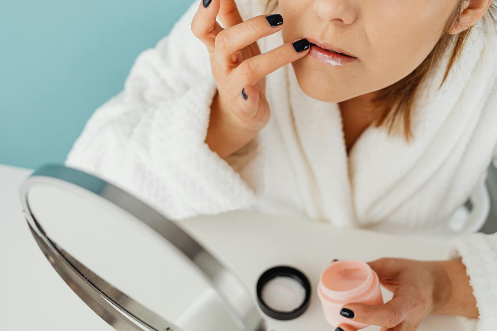Femeie aplicând tratament multitasking cu Azelaic Acid în fața oglinzii din baie