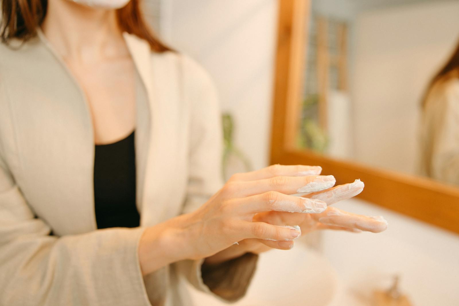 Mâini aplicând hidratant bogat în ceramide pentru a demonstra aplicarea de skincare reparator pentru barieră