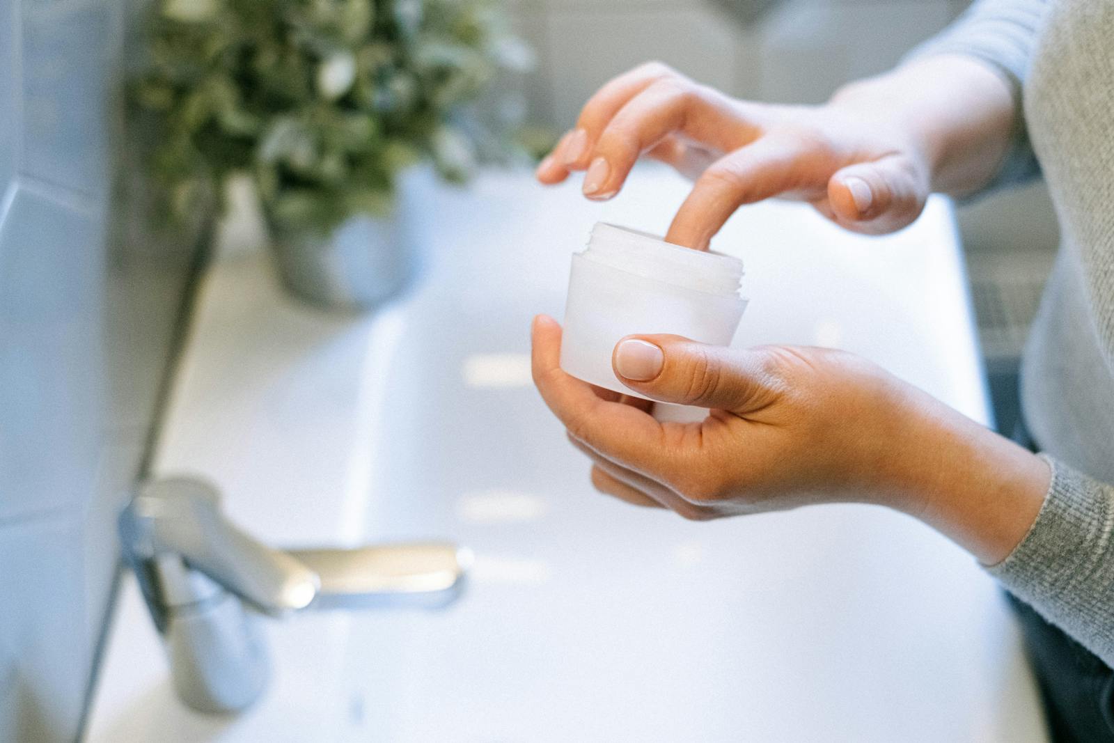 Mâini aplicând o cremă cu peptide ca parte a unei rutine anti-îmbătrânire de seară