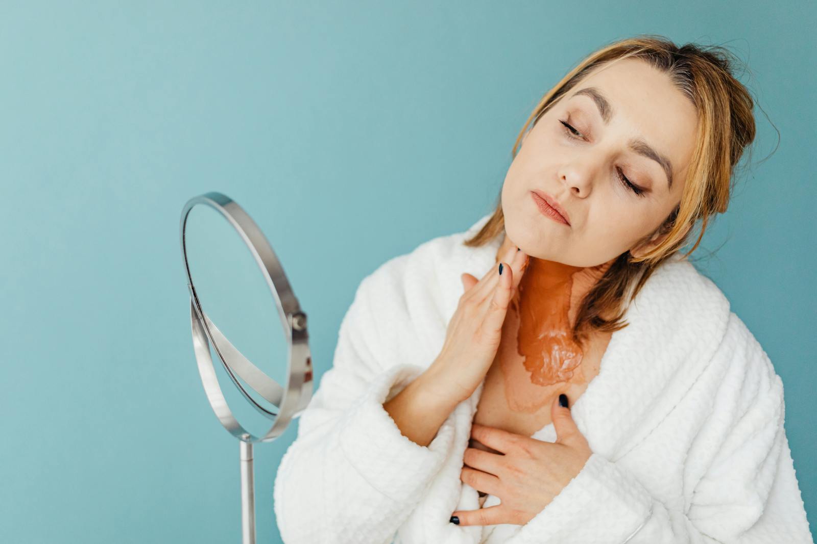 Femeie aplicând tratamentul BHA cu Salicylic Acid pe față în fața unei oglinzi de baie