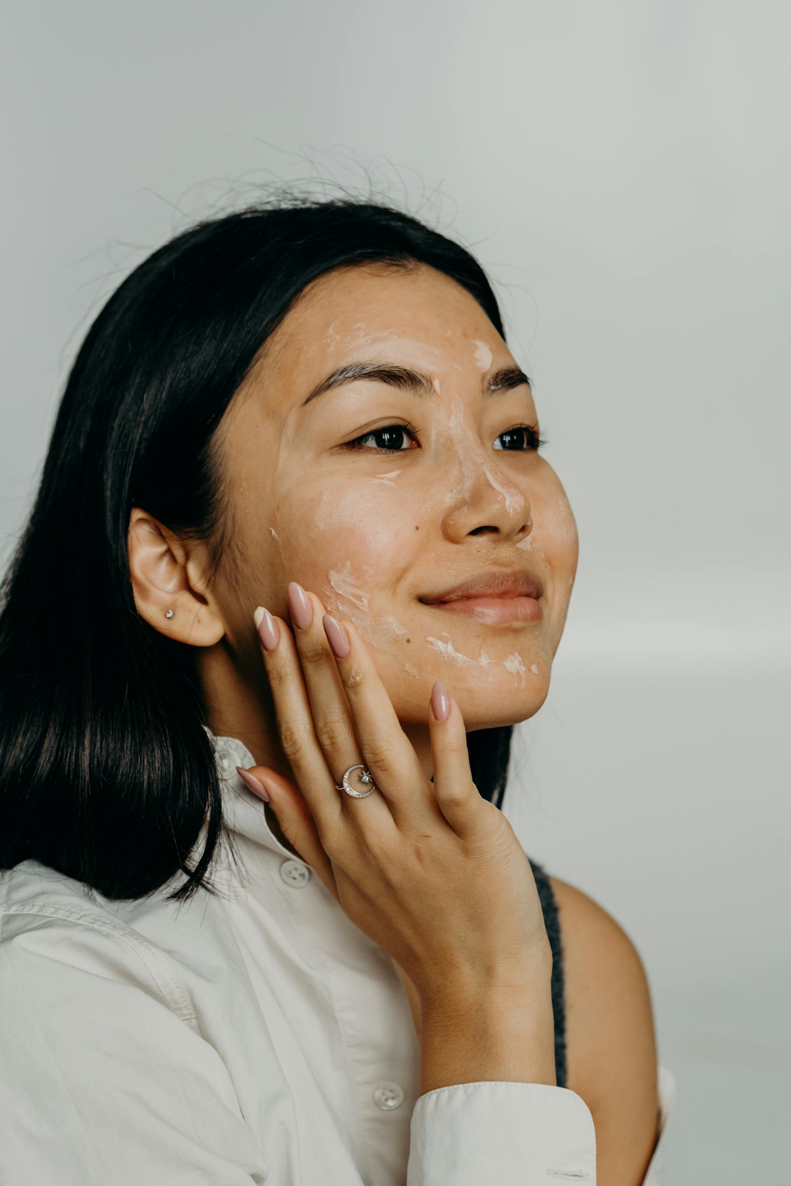Prim-plan al unei femei aplicând Retinol sau exfoliant într-o seară activă de skin cycling