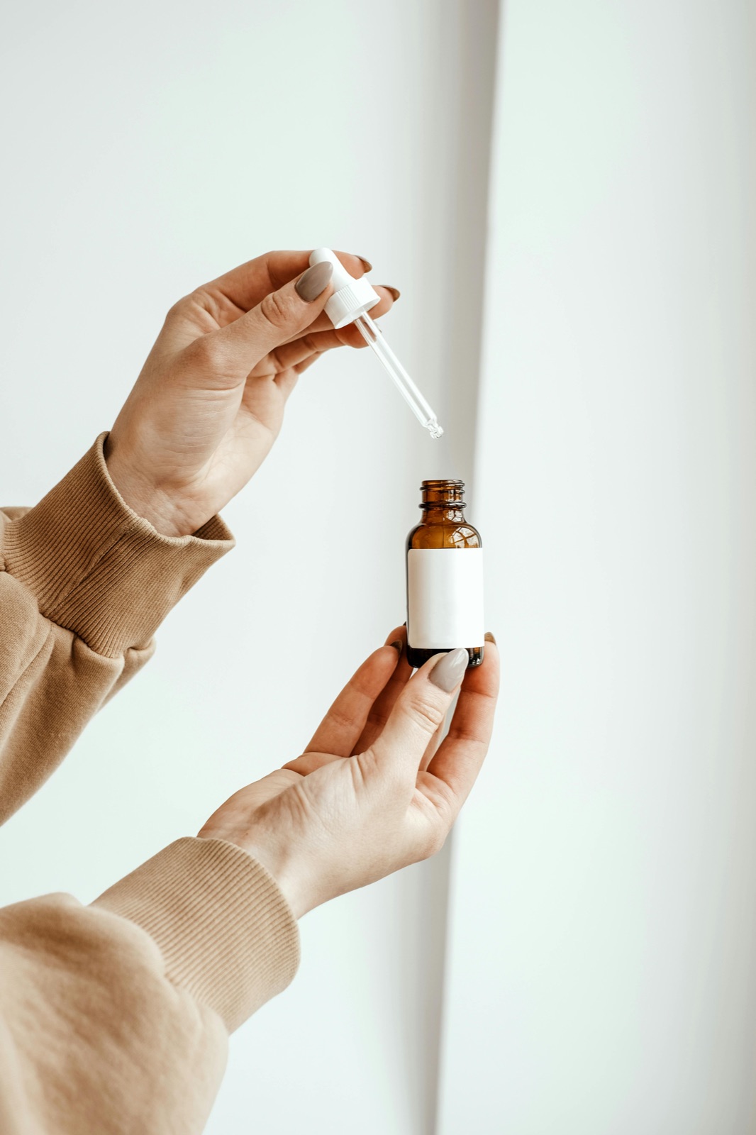 Mână ținând o sticluță cosmetică cu pipetă în timp ce citește lista actualizată de ingrediente INCI UE